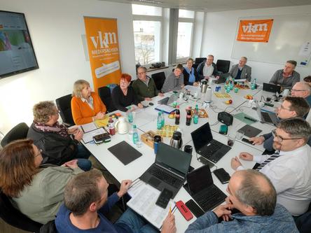 Viele Personen sitzen an einem Tisch und sprechen.